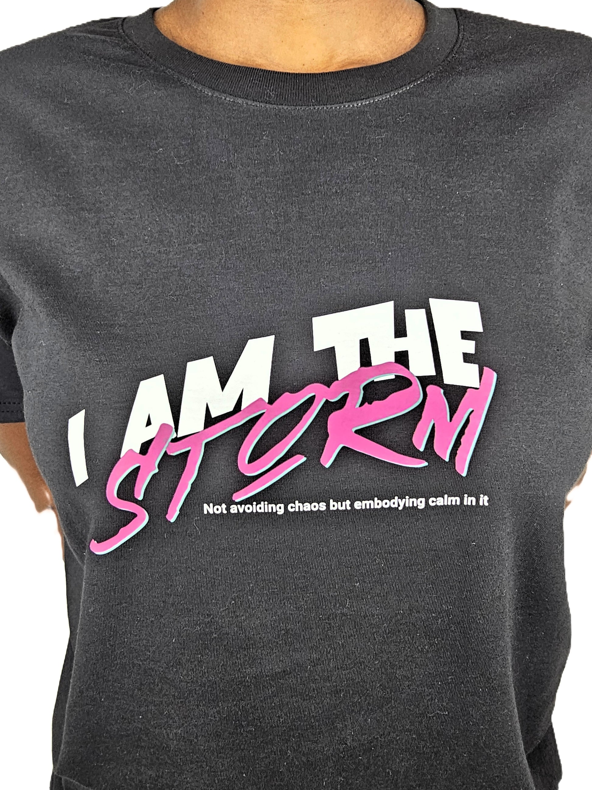 Black t-shirt with 'I AM THE STORM' text in white and pink on a plain background